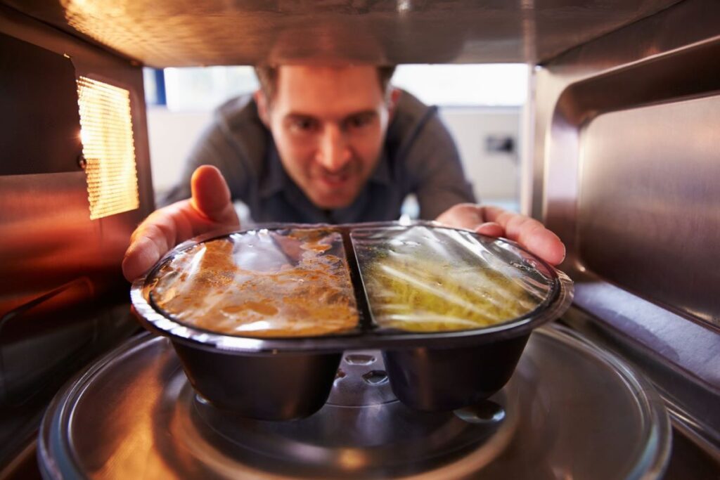 Man placing reheating a meal in a microwave oven