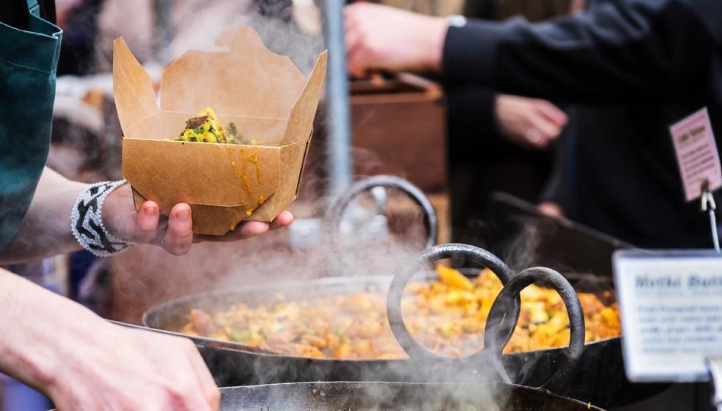 Street food vendor dishing food in a paper pack