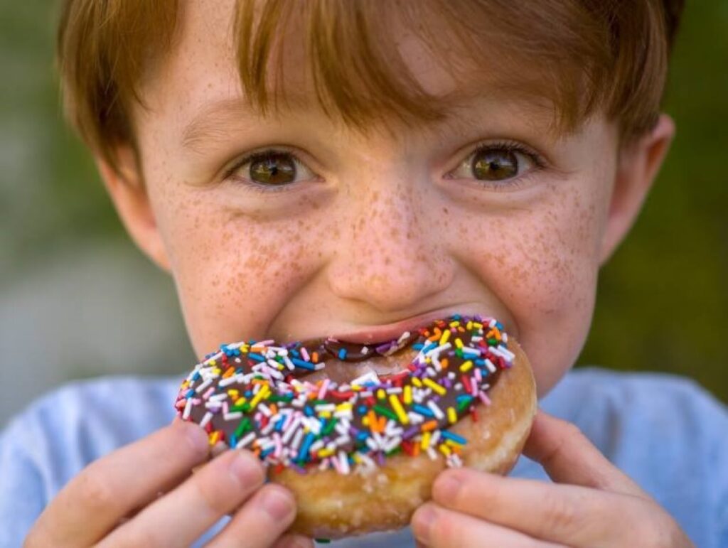 A kid mouthing an alluring donut