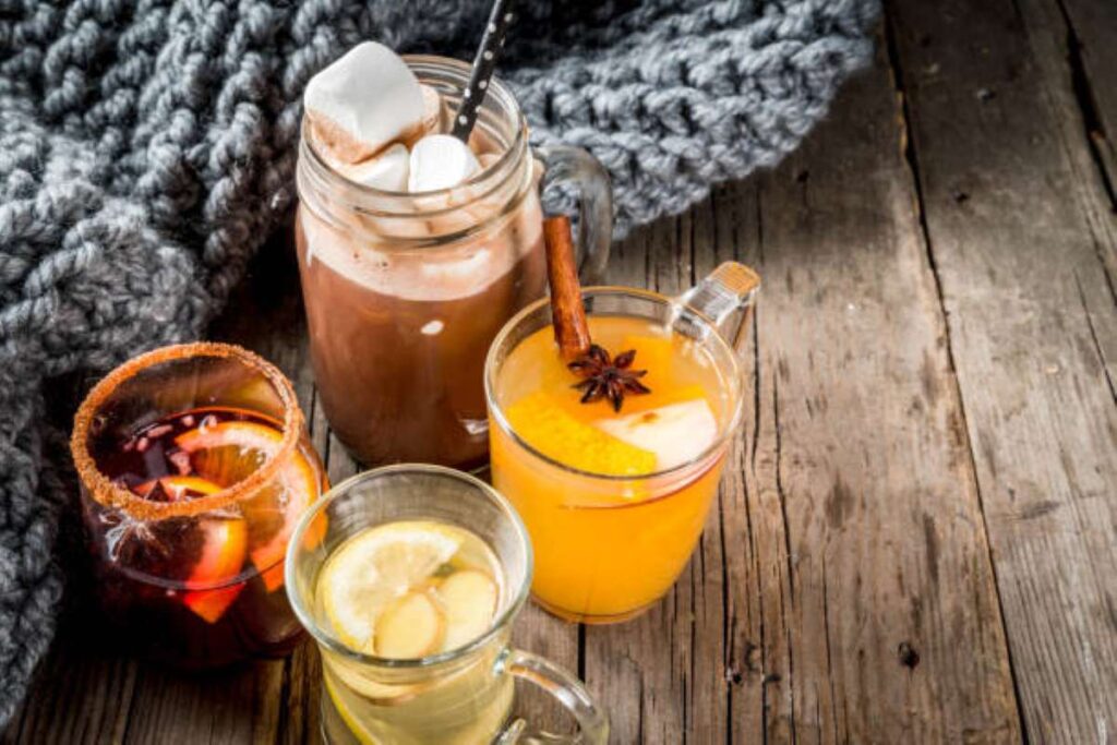 Selection of various winter traditional drinks: hot chocolate with marshmallow, tea with lemon and ginger, white pumpkin spicy sangria, mulled wine