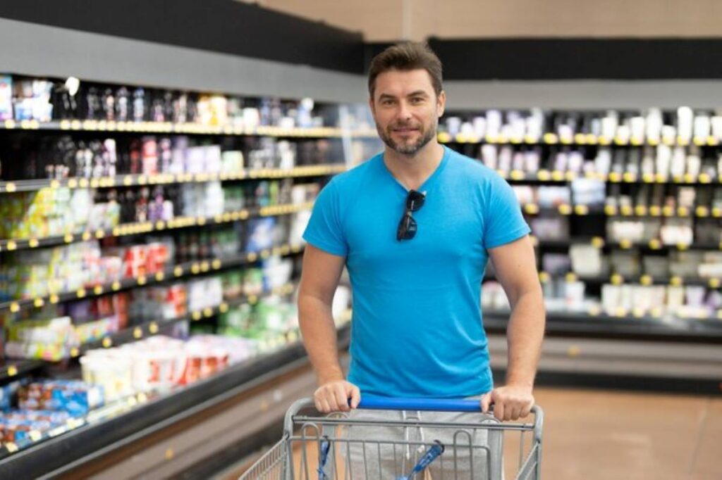 Handsome man hold shopping cart full of groceries man holds shopping basket store shopping sales