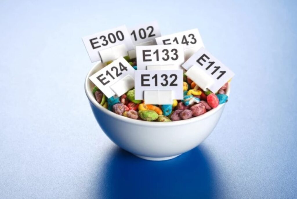 Bowl of multi-colored cereals with different additive labels
