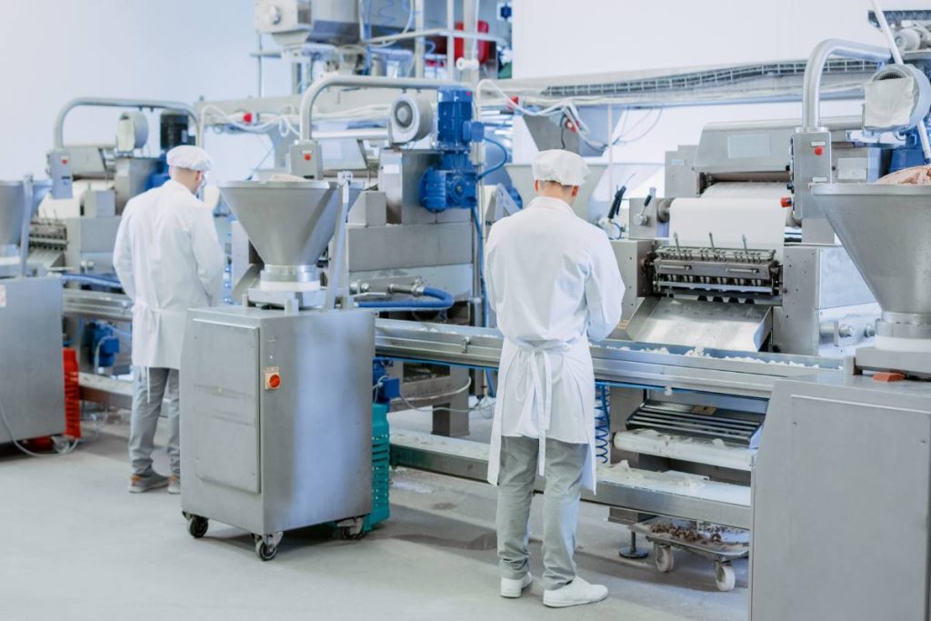 A worker in a factory with a machine for food processing