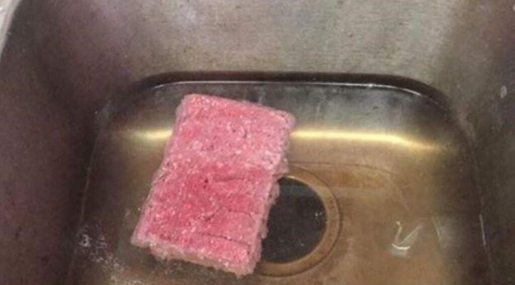 Someone thawing frozen beef directly in a sink