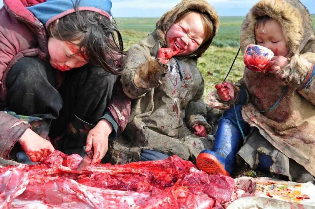 A Nenets family eating raw meat in the Yamal Peninsula of Siberia by Magdalena Skopek