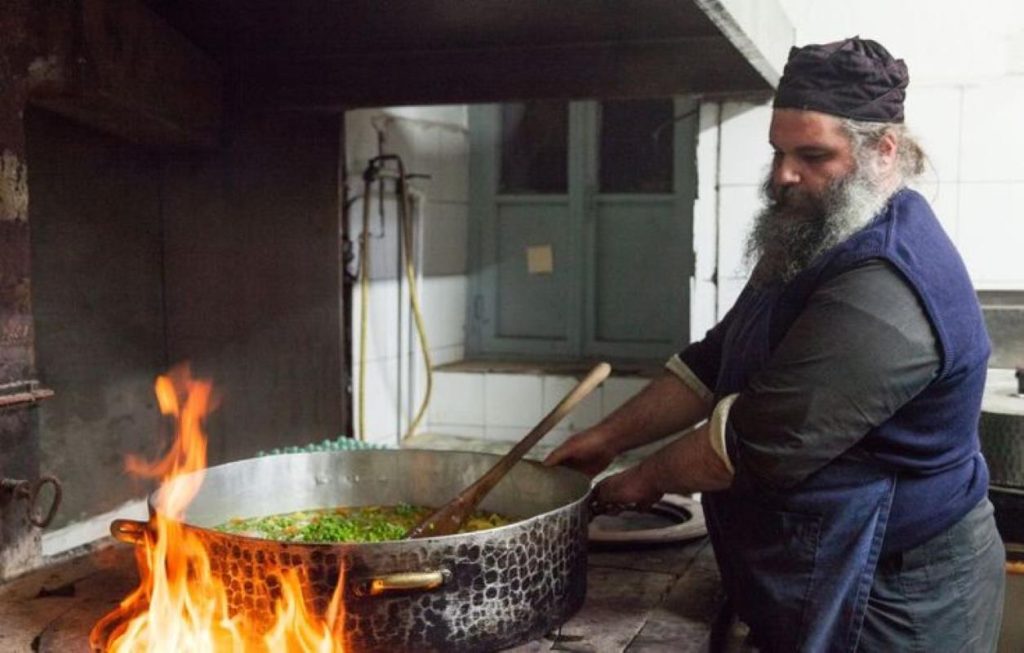 A Cretan monk cooking over an earthen fireplace