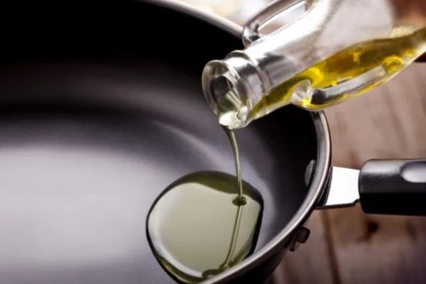Oil being poured into a clean frying pan