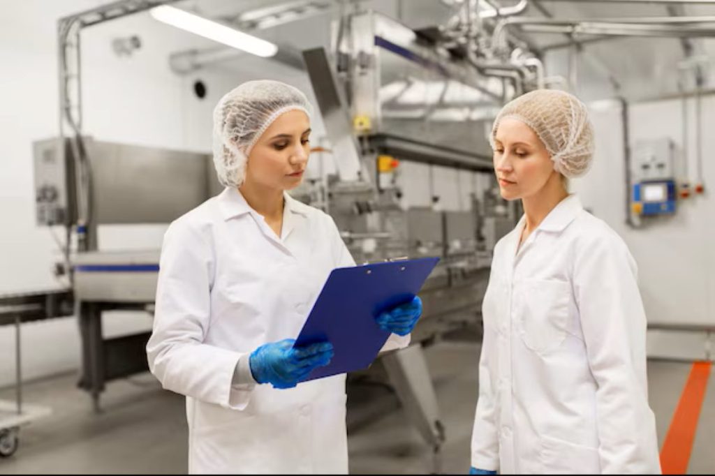 Manufacturing industry and people concept women technologists with a clipboard at an ice cream factory shop