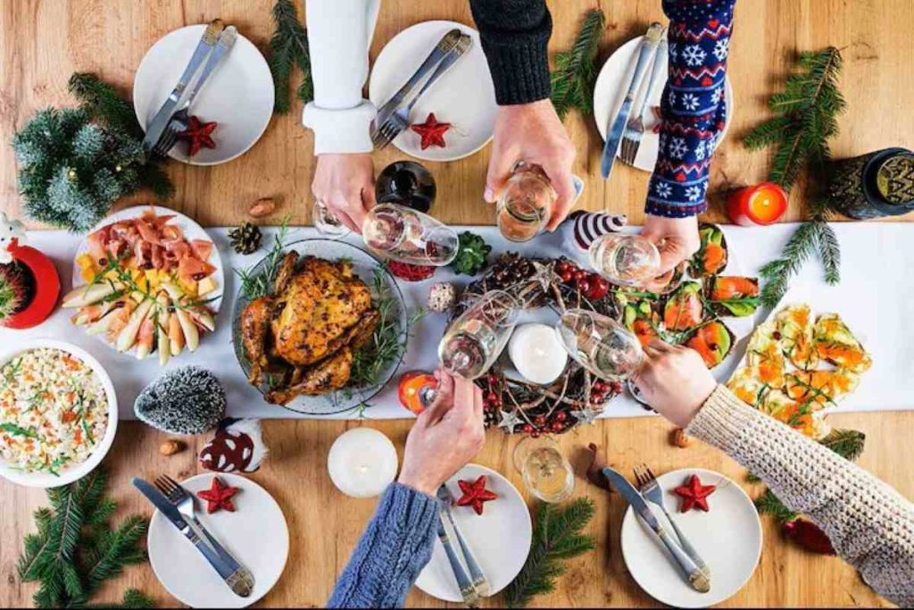 Baked turkey. Christmas dinner. The Christmas table is served with a turkey, decorated with bright tinsel and candles. Fried chicken, table. Family dinner. Top view, hands in the frame