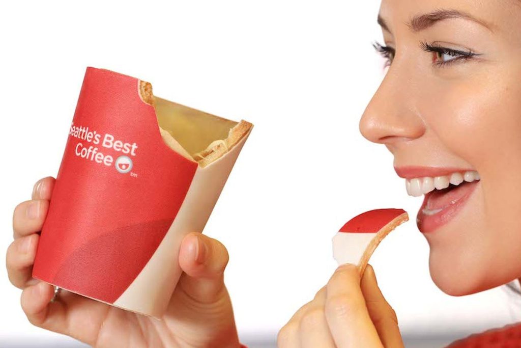 A woman biting a chunk off an edible coffee cup