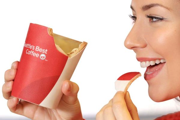 A woman biting a chunk off an edible coffee cup