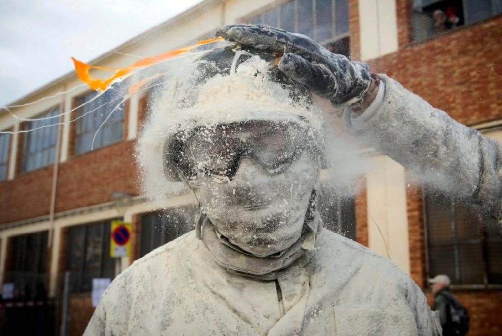 An Els Enfarinats celebrant have eggs smashed on their flour-covered helmet