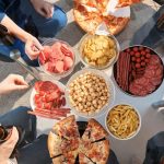a group of people standing around a table filled with food