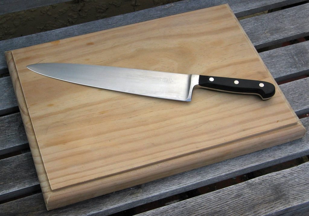 This is a wooden chopping board with a chef's knife on top