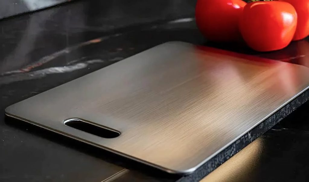 A clean titanium cutting board with tomatoes sitting next to it