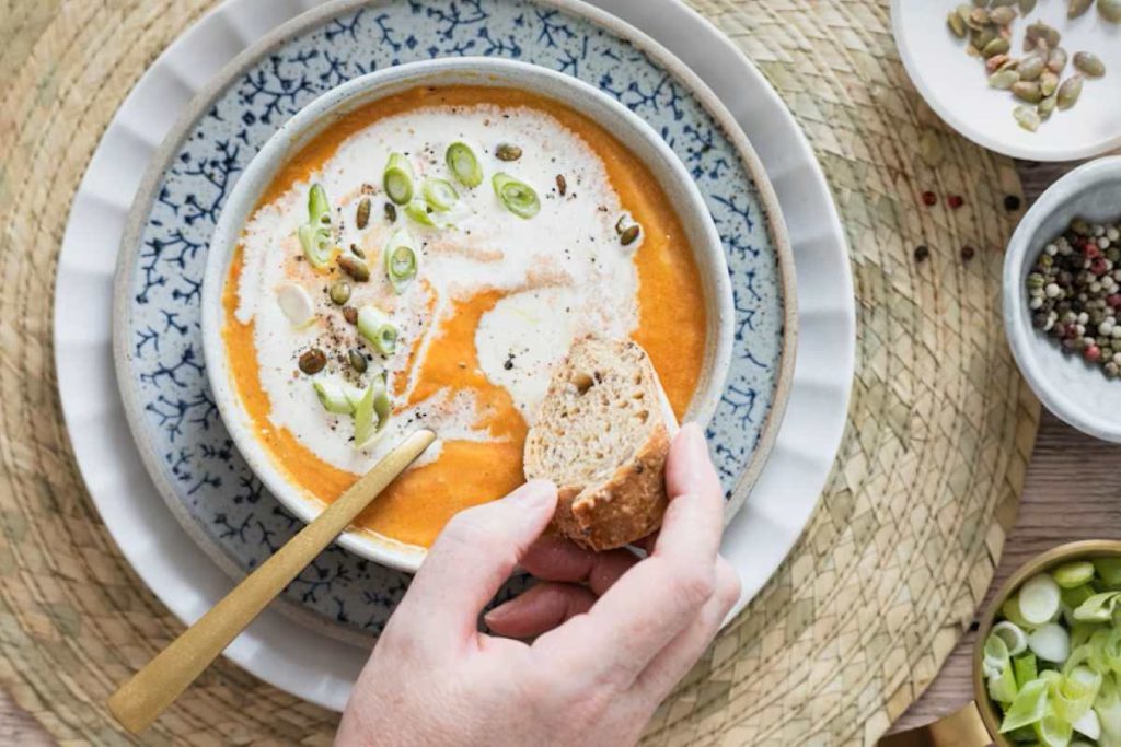 a person holding a spoon in a bowl of soup