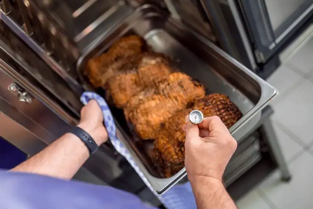 Checking the temperature of food baking in a stainless steel pan