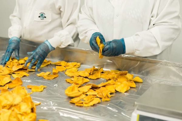 Two people in white shirts standing by a food work table