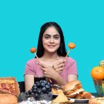 a woman holding a spoon in her mouth with food in front of her